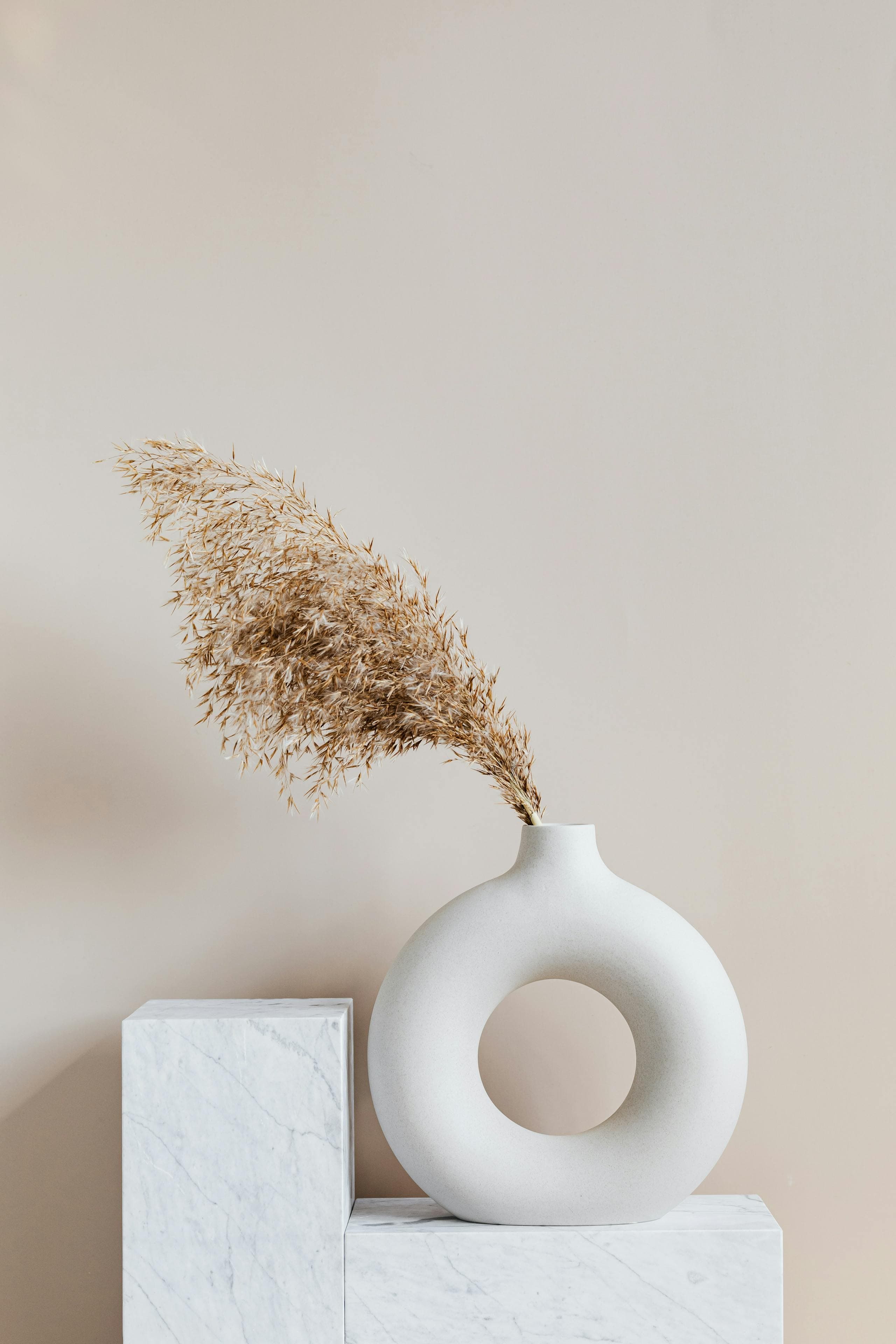 Minimal still life with ceramic vase and dried grass on marble - restraint, form, and calm systems