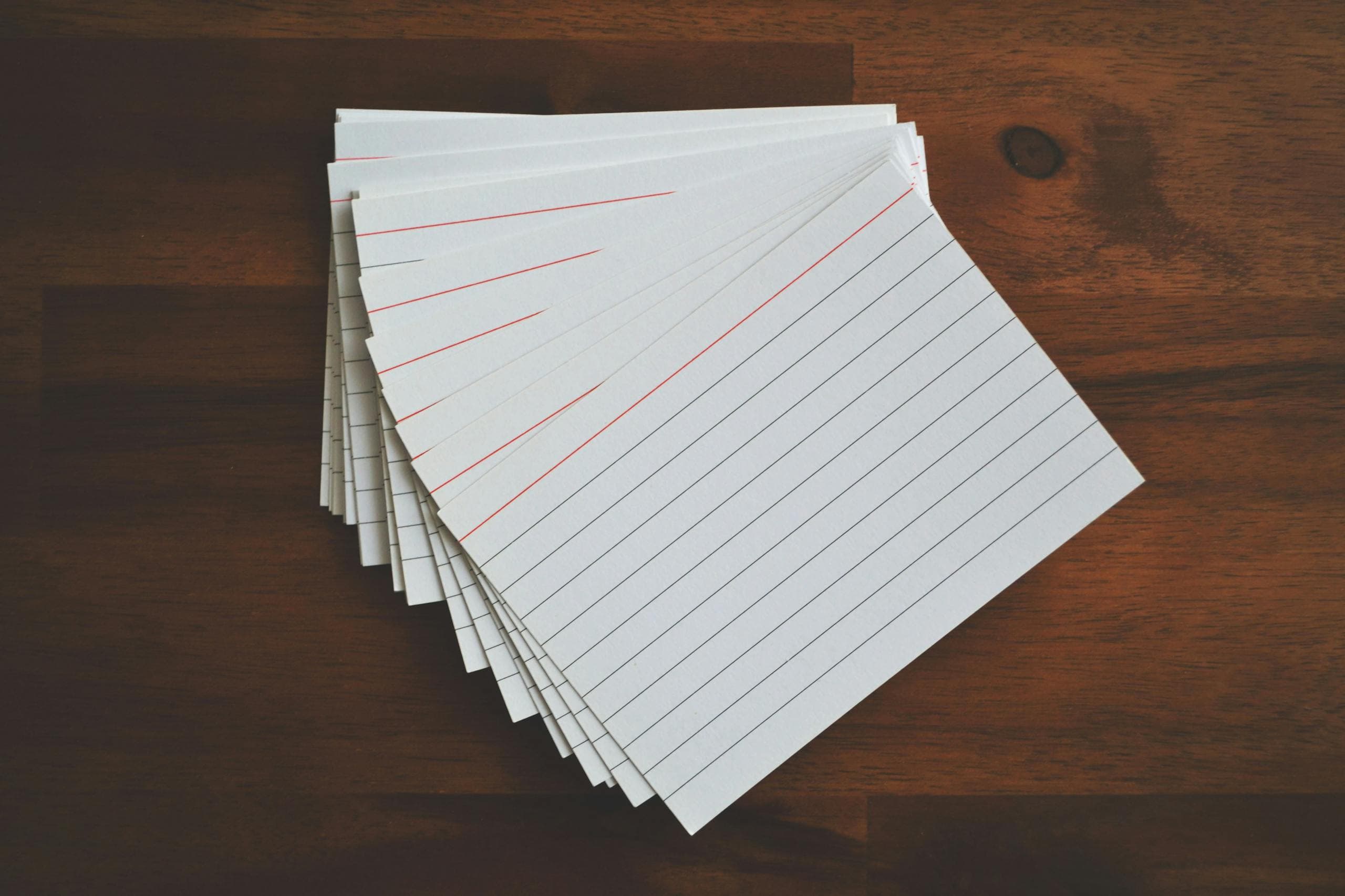 Ruled paper and index cards on a warm wood desk - planning and measurable signal